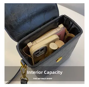 Detail showing internal capacity of the mini square bag with phone and makeup