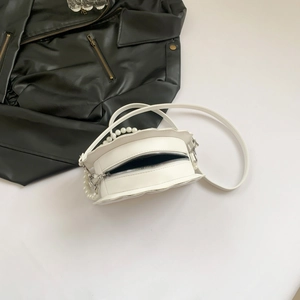 Detail of white PU shell bag with ruffled edges, pearl handle, and metal zipper closure