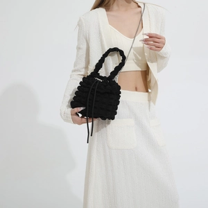 Detail of black pleated cloud bucket bag with textured bubble fabric and silver chain