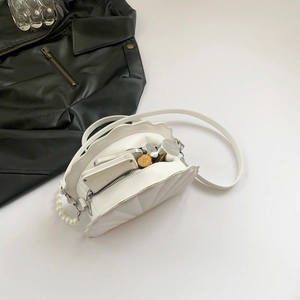 Detailed interior of shell-shaped PU handbag with pearl handle and daily essentials