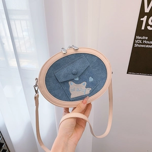Detail of blue denim oval crossbody bag with cute cat embroidery and pink leather trim