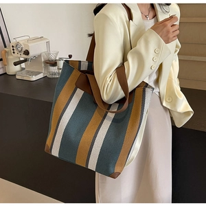 Detail of color-block striped canvas tote bag with reinforced leather corners and wide strap