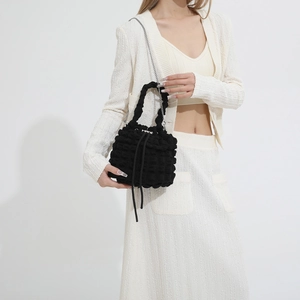 Close-up of black bubble textured bucket bag with drawstring and silver chain strap