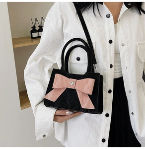 Close-up of black pleated mini bag featuring a large pink bow with heart-shaped crystal
