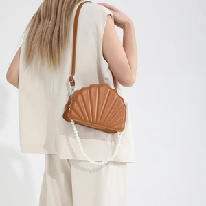 Brown shell-shaped crossbody bag featuring detailed stitching and a pearl handle strap