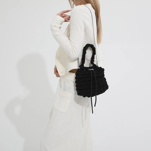 Detail of black pleated cloud bucket bag with textured fabric and silver chain strap
