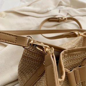Vue détaillée des crochets dorés et des finitions en similicuir beige du sac en paille