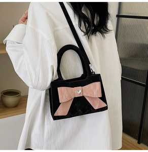Detail of crossbody bag featuring a pink satin bow and heart-shaped rhinestone buckle