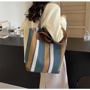 Detailed close-up of vertical striped canvas tote bag with brown leather trim details