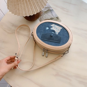 Detail of blue denim crossbody bag featuring cat patches, heart embroidery and leather trim