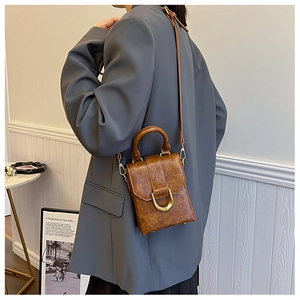 Detail of vintage brown leather handbag with gold D-ring buckle and shoulder strap