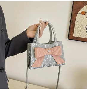 Detail of silver metallic wrinkled texture bag with large pink bow and heart crystal