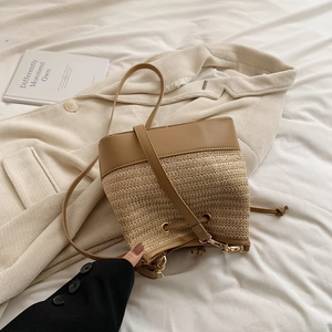 Détail de la texture en paille tressée et du cuir kaki haut de gamme sur le sac seau