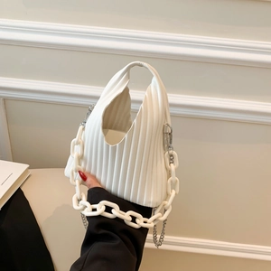 Close-up of beige pleated PU shoulder bag with bold white chain and metal strap