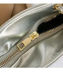 Détail macro de la fermeture éclair dorée sur le grand sac argenté à texture métallique