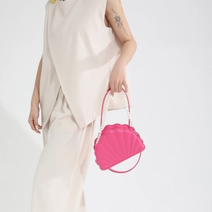 Pink shell-shaped handbag with pearl strap detail on a minimalist summer outfit