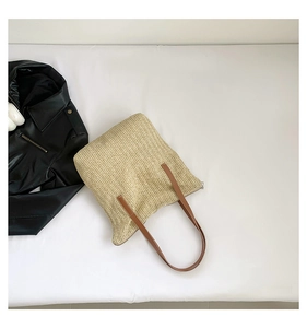 Détail du sac cabas en paille tressée beige avec anses en cuir marron sur blanc