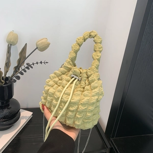 Detailed view of light green popcorn textured bucket bag with silver drawstring metal buckle