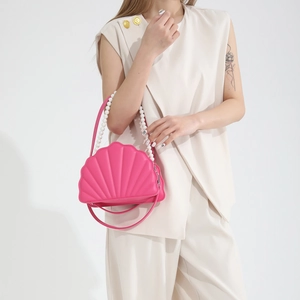 Detail of shell-shaped pink PU leather bag with large faux pearl handle and slim strap