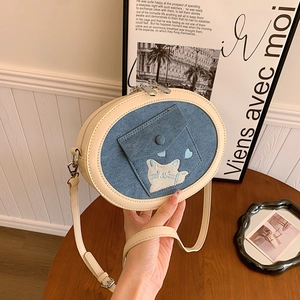 Detail of blue denim crossbody bag featuring cat embroidery and cream leather strap