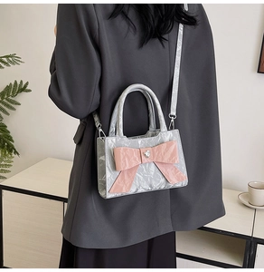 Silver metallic mini crossbody bag featuring a pink bow and heart rhinestone on a model