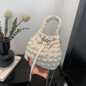 Macro detail of creamy white bubble textured pleated bucket bag with drawstring closure