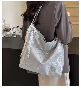 Close-up of silver metallic textured bucket bag featuring a delicate white lace bow detail