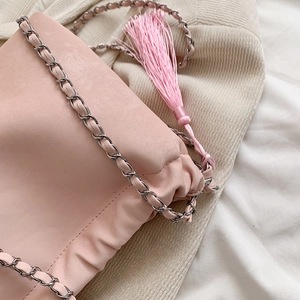 Detail der rosa Plissee-Tasche mit gewebtem Silberkettenriemen und langer Zierquaste