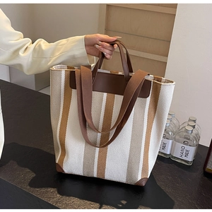Detailed view of striped canvas tote bag with leather handles and reinforced bottom corners