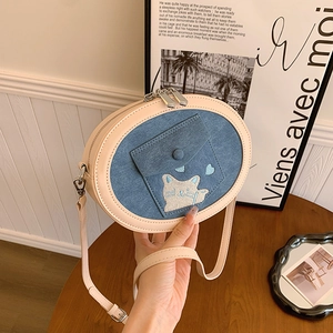 Detail of a beige and denim blue round crossbody bag with cute cat embroidery and zipper