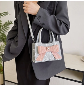 Close-up of silver pleated handbag with pink bow and heart-shaped rhinestone detail