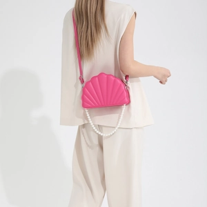 Detail view of pink shell-shaped crossbody bag featuring white pearl chain strap