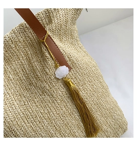 Détail du tissage en paille avec breloque fleur blanche et gland doré soyeux