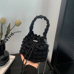 Detail of black pleated cloud bucket bag featuring textured bubble fabric and silver chain
