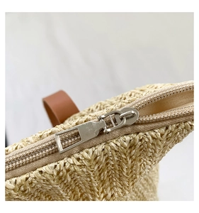 Détail du sac en paille tissée avec fermeture éclair en métal argenté et cuir brun