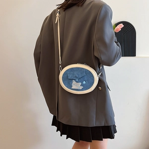 Detail of blue denim oval crossbody bag featuring cute cat embroidery and chain strap