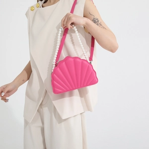 Detail of rose pink shell crossbody bag with pearl handle and quilted texture