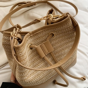 Détail de la texture en paille tressée avec garniture en cuir et boucles dorées du sac