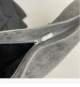 Detail view of the smooth metallic zipper and vintage silver texture on the shoulder bag