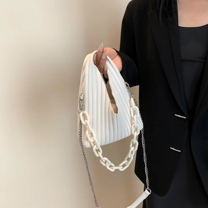 Close-up of white pleated PU handbag featuring chunky acrylic chain and silver shoulder strap