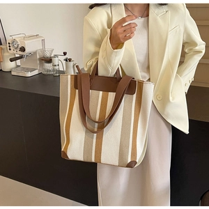 Detailed view of wide canvas tote with contrast stripes and leather trim accents