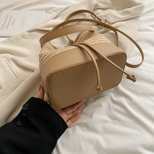 Détail du sac seau en paille tissée kaki avec cordon de serrage et poignée en cuir