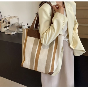 Detail of canvas tote bag with contrast stripes, leather handles and reinforced base