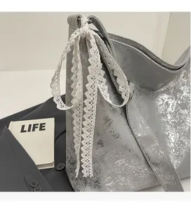 Detail of silver bucket bag featuring lace bow pendant and retro distressed texture