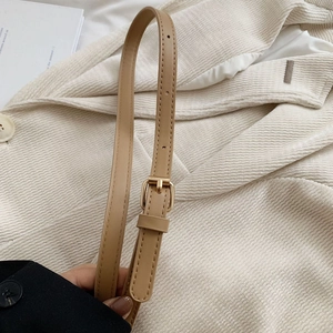 Détail d'une bandoulière réglable en cuir kaki avec boucle en métal doré et couture