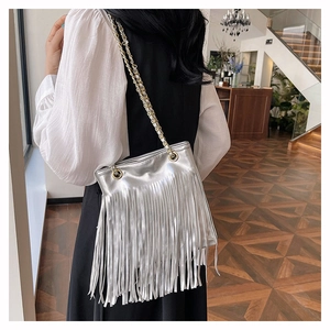 Sac à bandoulière argenté à franges avec chaîne porté par un mannequin en intérieur