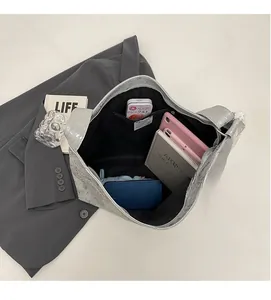 Top view showing the large interior capacity of the silver tote bag with tablet and books