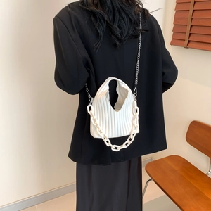 Detail of white pleated PU leather bag with chunky chain handle and metal shoulder strap