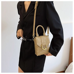 Close-up of khaki mini handbag featuring textured leather and a gold D-shaped buckle