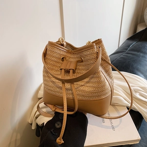 Détail du sac seau en paille tressée avec cordon en cuir marron et boucles dorées